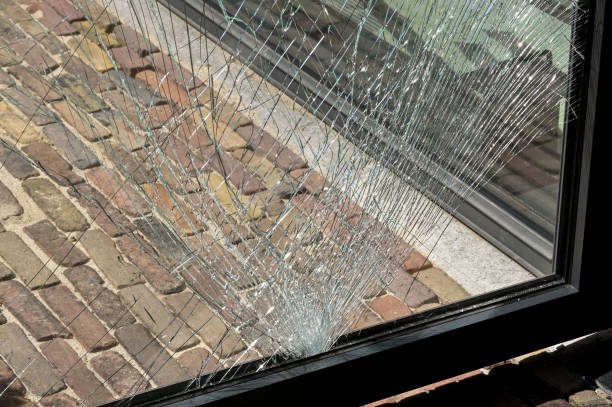 Close up view of cracks in a pane of toughened glass in a door after being struck by an object. No people.